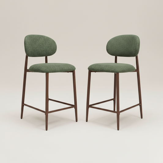 Two modern couter chairs with green upholstered seats and backs and dark brown wooden legs, shown on a light beige studio background.